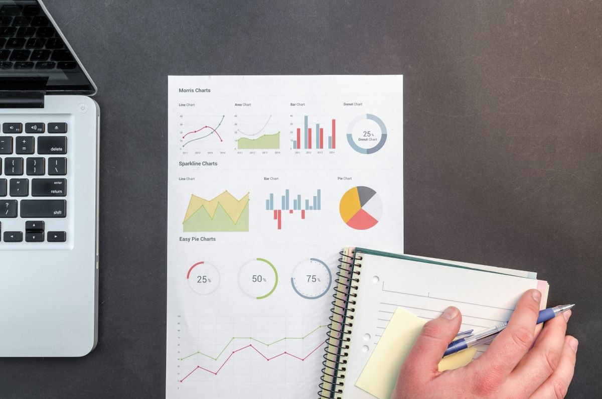 Printed charts and graphs on a desk with a laptop